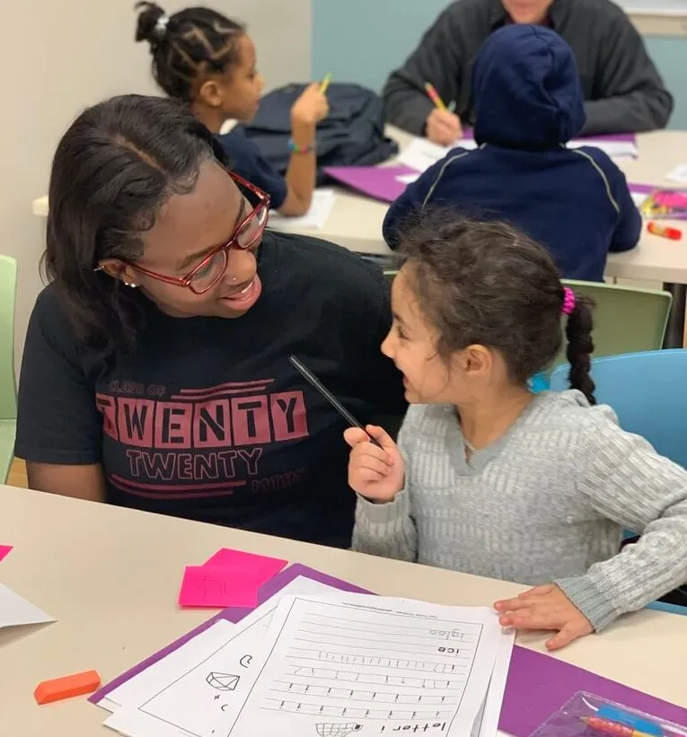 Student smiles at tutor while working on schoolwork