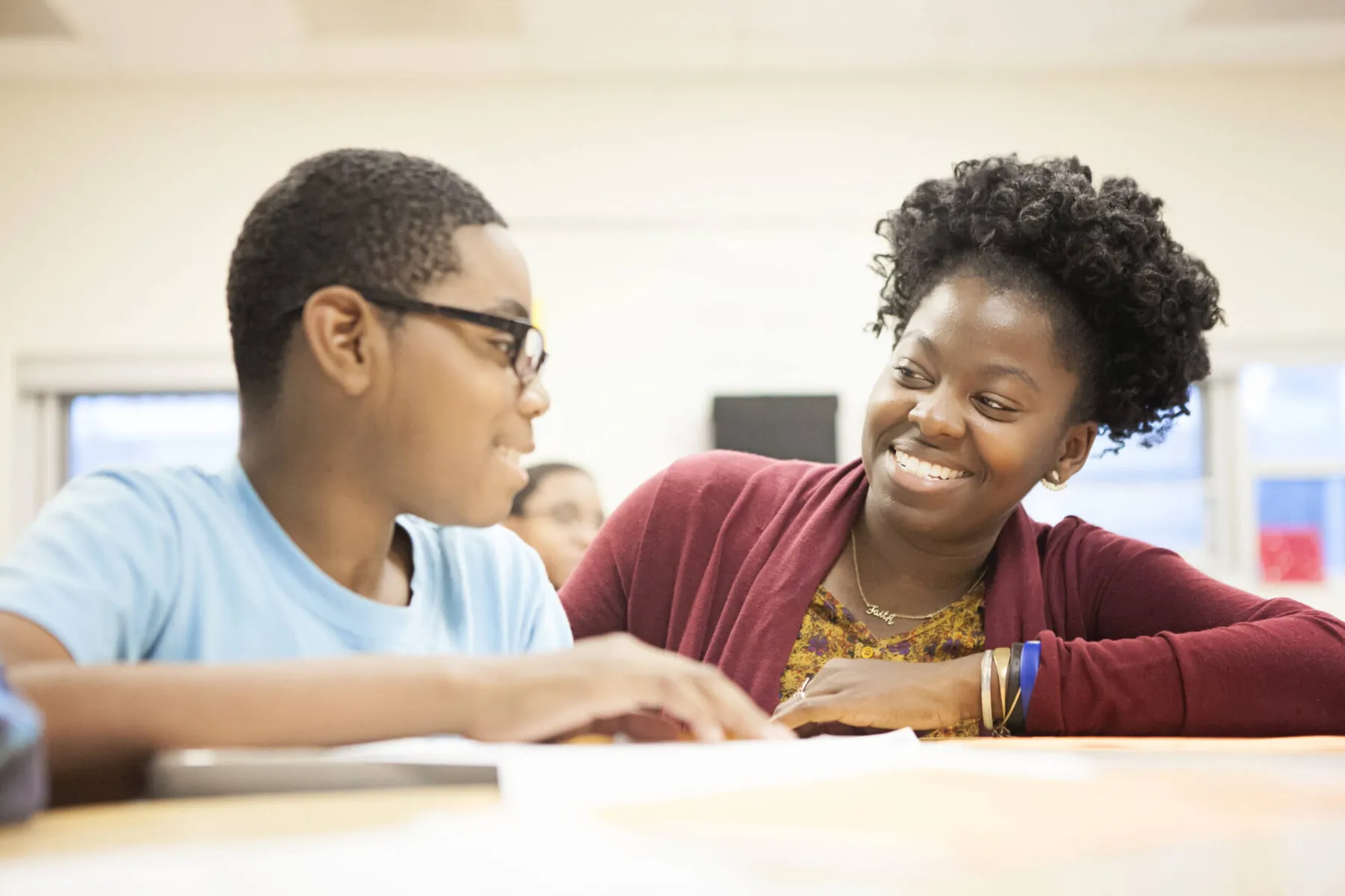 Woman helping a student write at a table