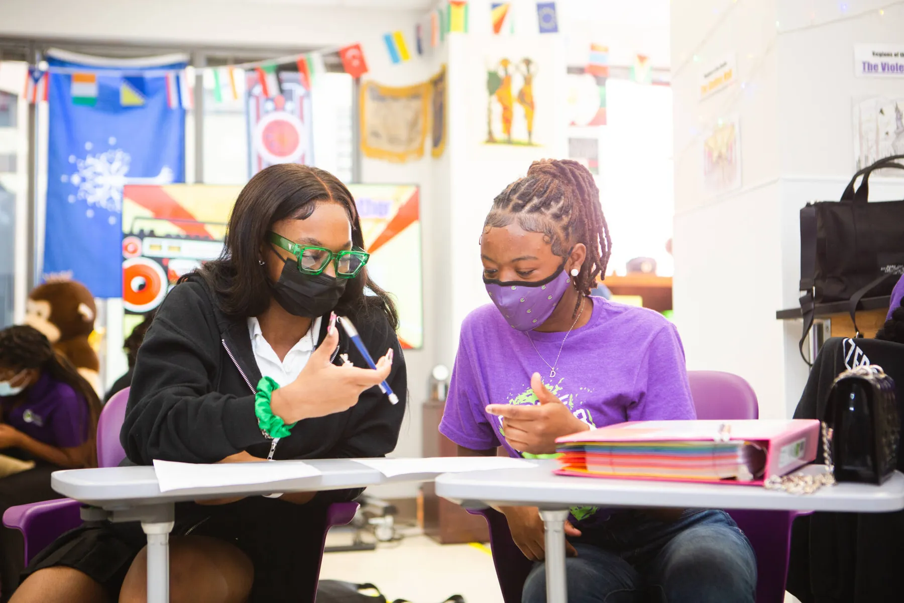 Two masked women writing together at a table