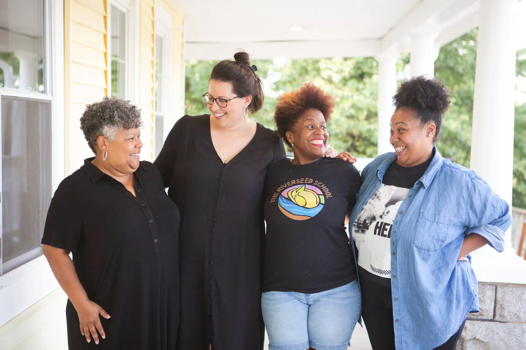 Four women standing together and smiling indoors