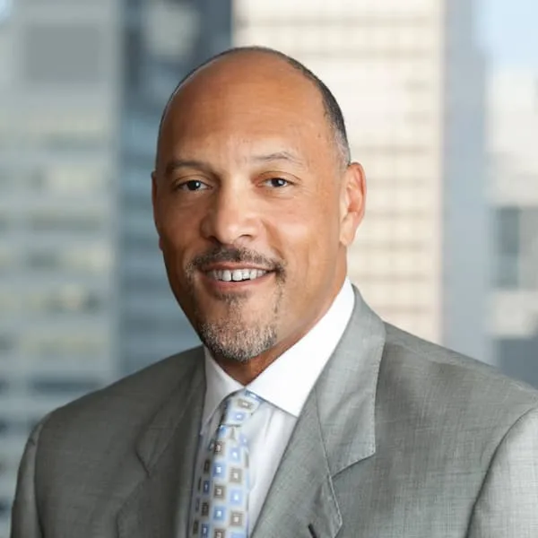 Portrait of a smiling man in a light gray suit with a patterned tie
