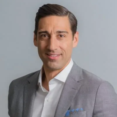 Man in a light gray suit against a plain gray background