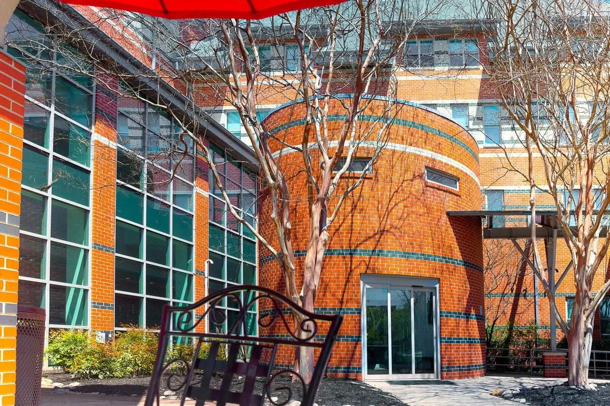 Red-brick institutional building with tall glass windows and bare trees