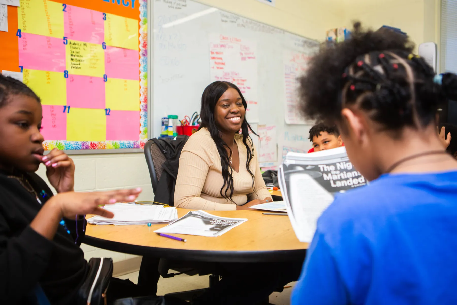 Woman tutoring a student at a table while another student sits nearby