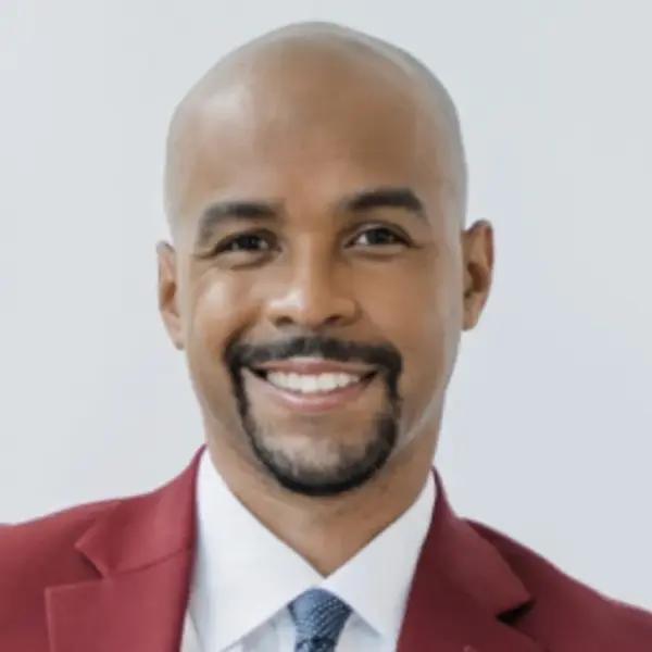 Portrait of a smiling bald man with a trimmed beard wearing a red jacket