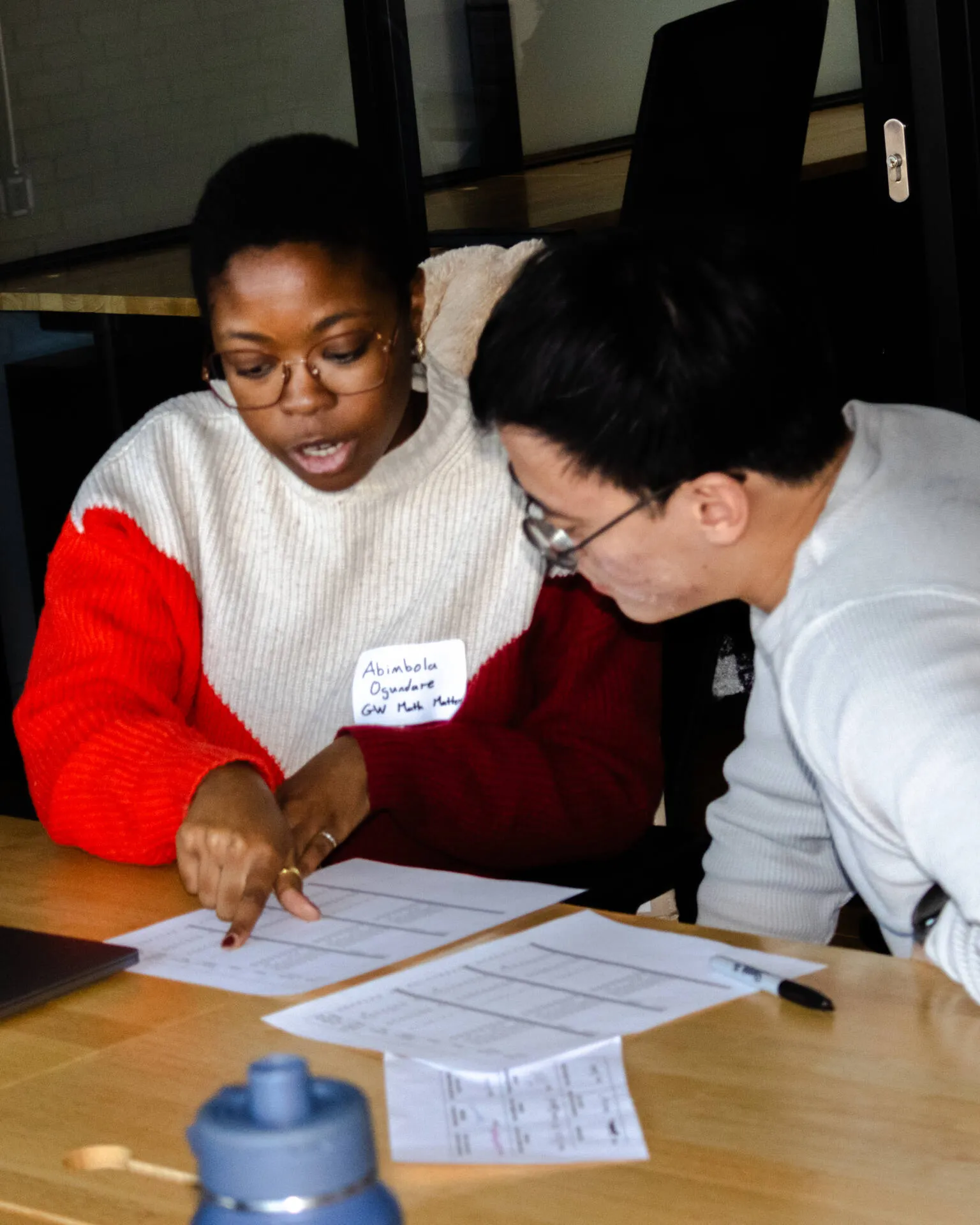 Woman and man helping a student write at a table