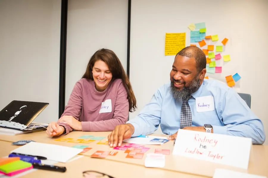 Woman and man smiling while working with papers at a table