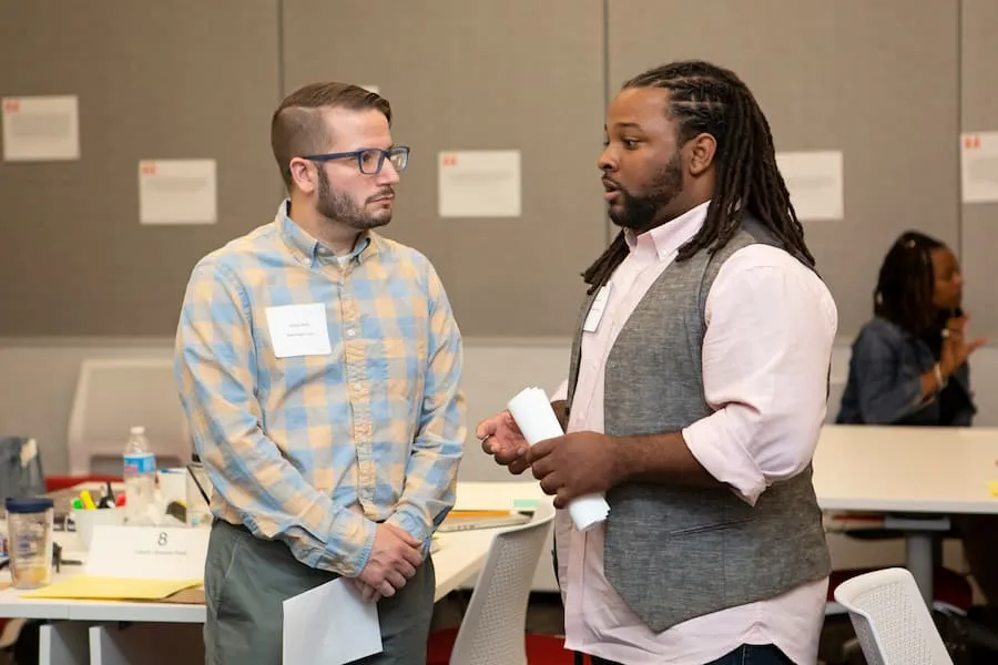 Two men standing and talking at an indoor networking event