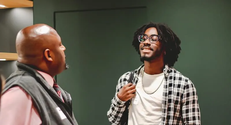 Two men talking indoors, one holding a microphone