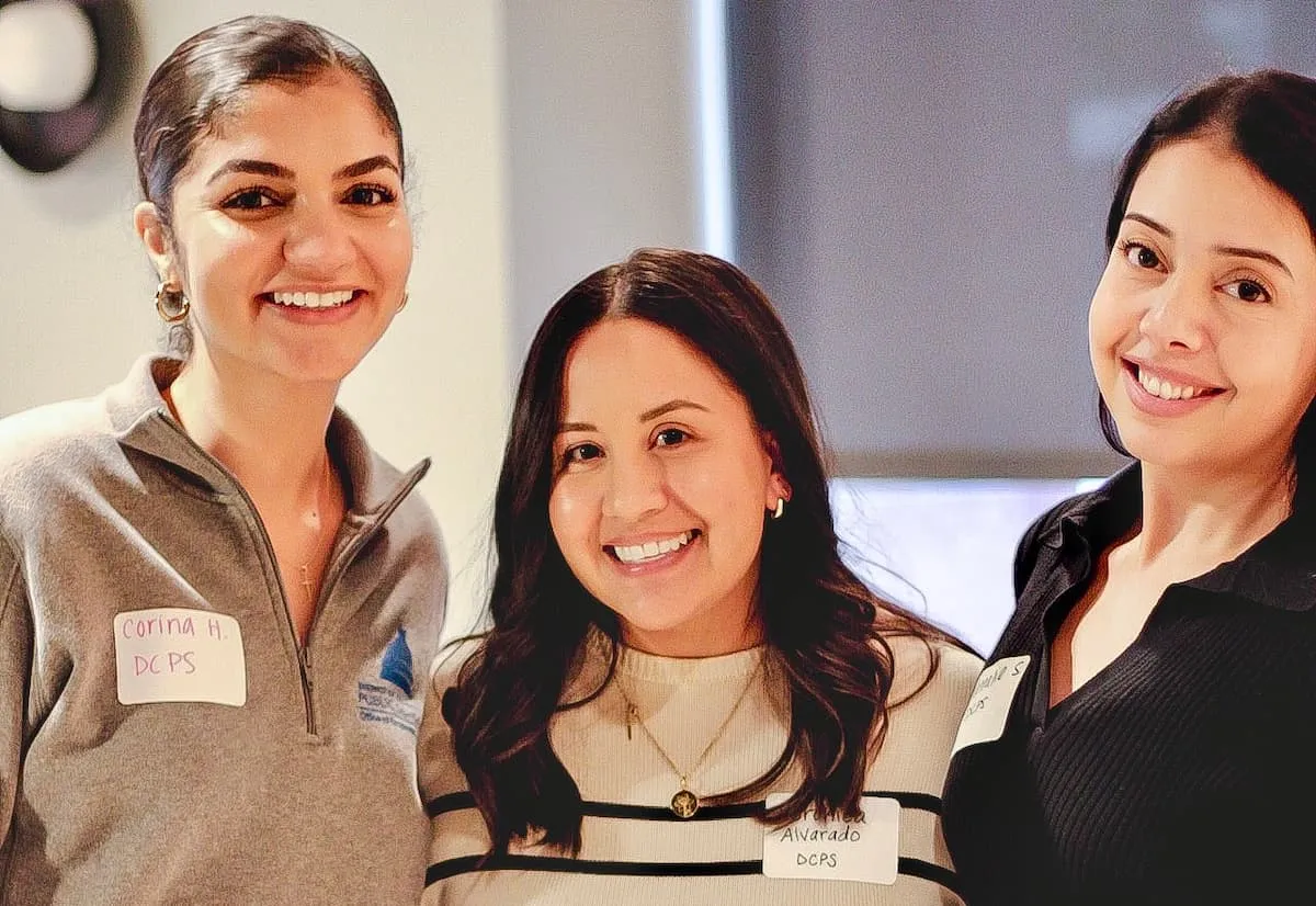 Three smiling women posing together indoors