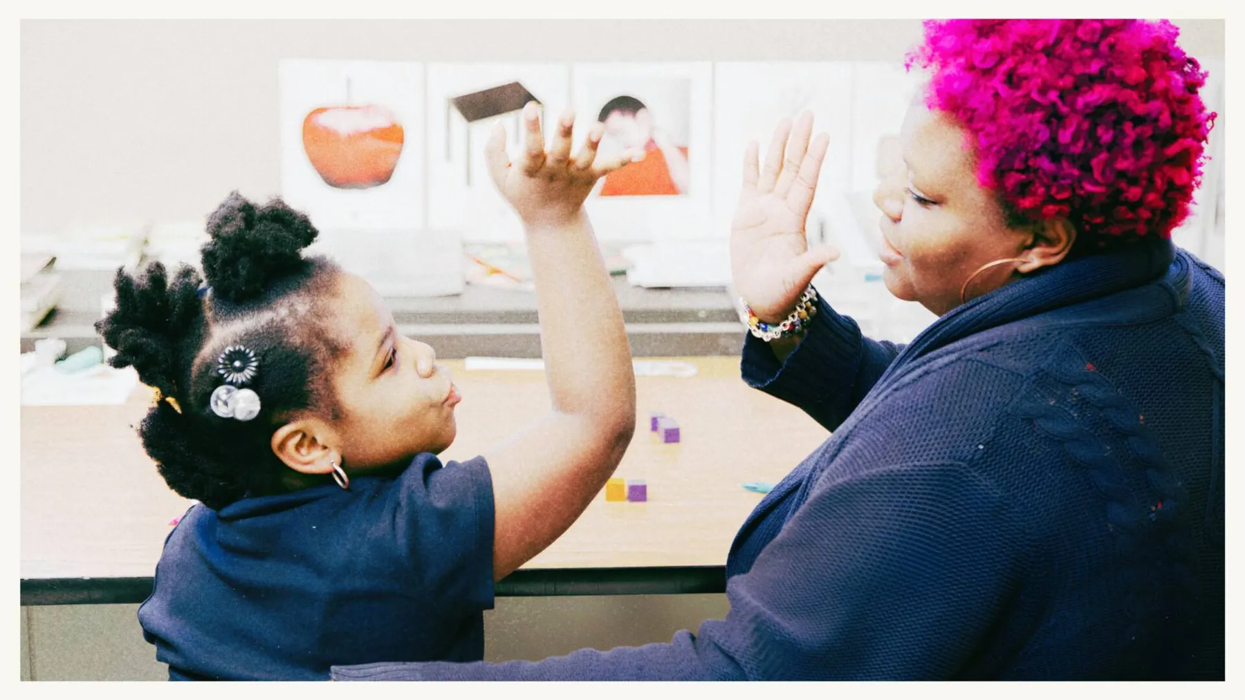 Woman and child raising their hands for a high-five at a table - CitySchools Collaborative Woman and child raising their hands for a high-five at a table